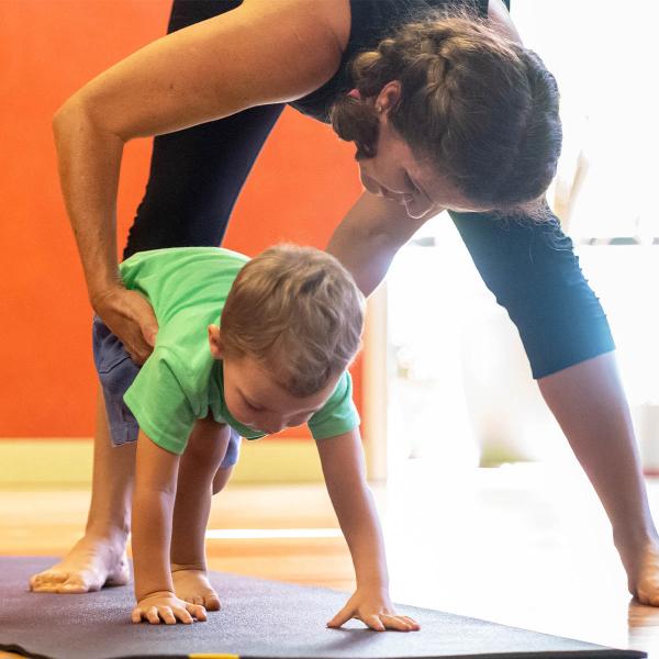 Woman helping child with yoga pose