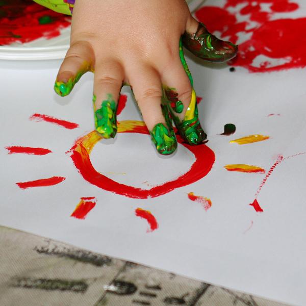 Child finger painting on white paper.