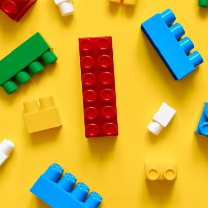 Image of different colored lego bricks against a yellow background. 