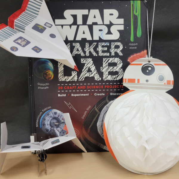 Image of two paper planes, a BB-8 party decoration in the foreground and a Star Wars Maker Lab book in the background. 