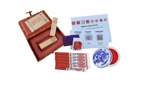 Ornate red box with 2 ivory name seals within, next to instructions on how to make a name stamp, red markers, red ink stamp and a 
