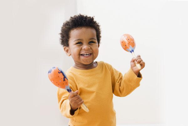 A toddler smiling and holding maracas