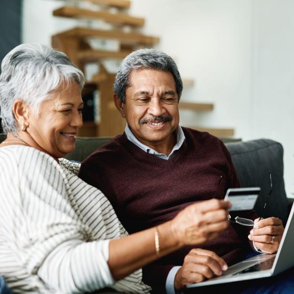 Older couple in front of laptop with credit card.