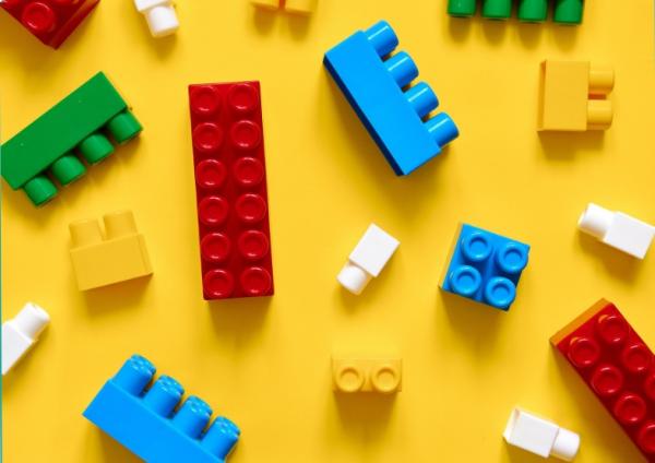 Colorful building blocks scattered on yellow background 