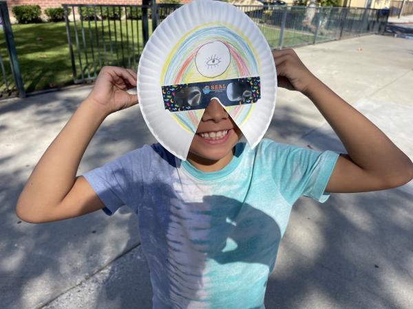 Child wearing solar eclipse viewing glasses and eclipse-inspired art