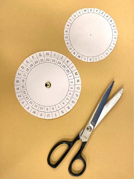Two cipher wheels and scissors on a table 