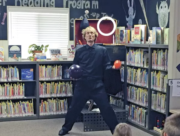 Man juggling three balls in library.