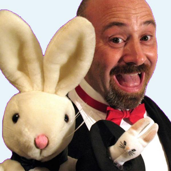 A man dressed up as a magician holding a bunny