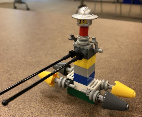 A toy built from LEGO bricks featuring a silver face with hat on top of a brick tower with four cones sticking out to the sides.