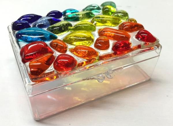 Clear box with lid and colorful glass rocks on top 