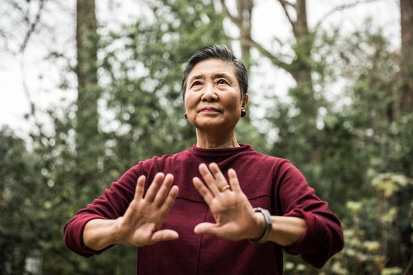 Asian person is in the outdoors doing Tai Chi