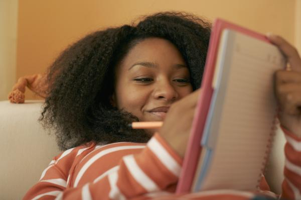 Teen girl smiling and journaling in notebook