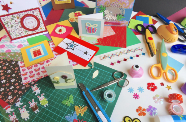 Multiple holiday cards with craft supplies on table
