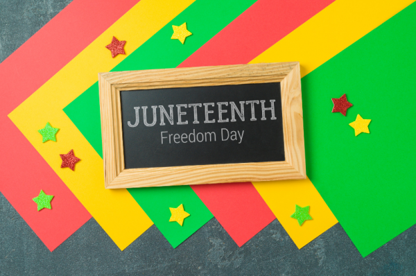 Red, green, and yellow paper on table with a small frame in between reading JUNETEENTH Freedom Day 