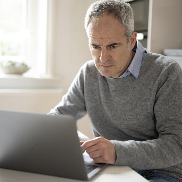 Older man staring intently at laptop.