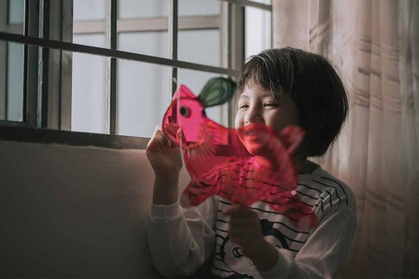 Child drawing a red rabbit on a window.