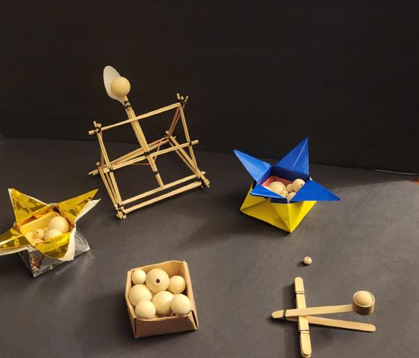 Two catapults built from craft sticks and three boxes of small white balls.