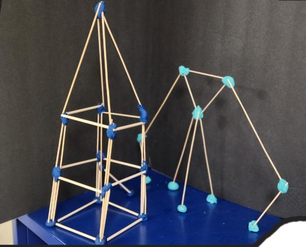 Two structures made from thin sticks connected with blue tape.
