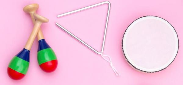 a pair a maracas, a triangle, and a drum on a pink background