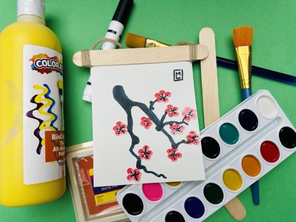 Small painting of cherry blossom tree with painting materials scattered on table 