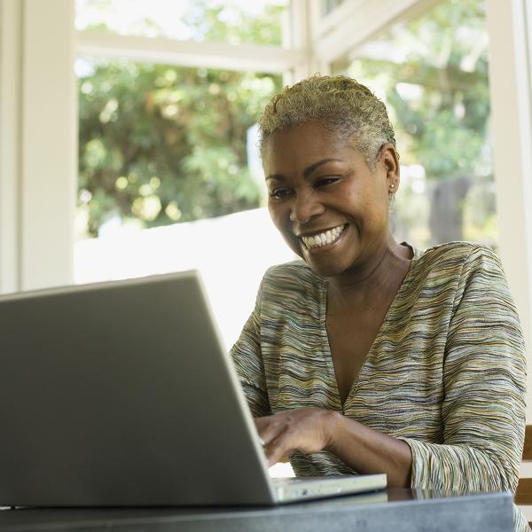 smiling older african american working on laptop in home setting