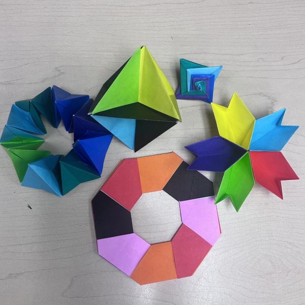 Multiple, multi-colored origami models arrayed on a table.