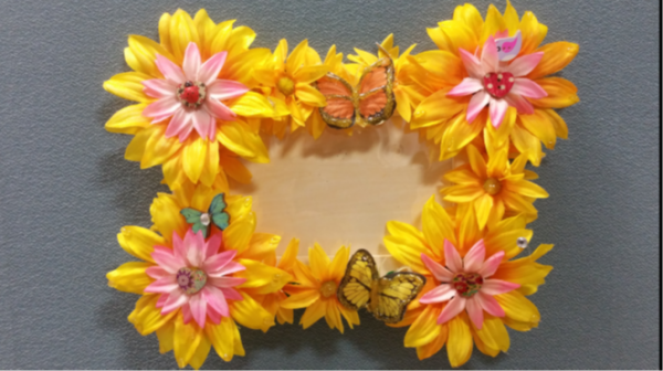 An empty picture frame covered in yellow flowers and butterflies.