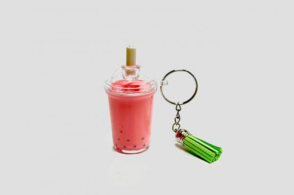 Photo of a mini boba keychain with pink filling and a lime green tassel on a white background.