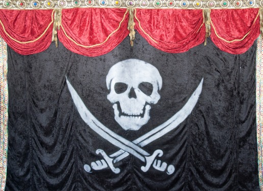 A pirate flag below red stage bunting.