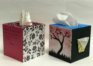 Tissue boxes decorated with poetry, patterned paper, and drawings.