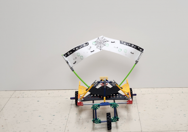 A vehicle made of Knex building toys with three wheels and a white banner sail.