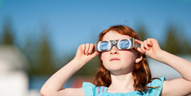 Girl wearing solar eclipse glasses viewing solar eclipse.