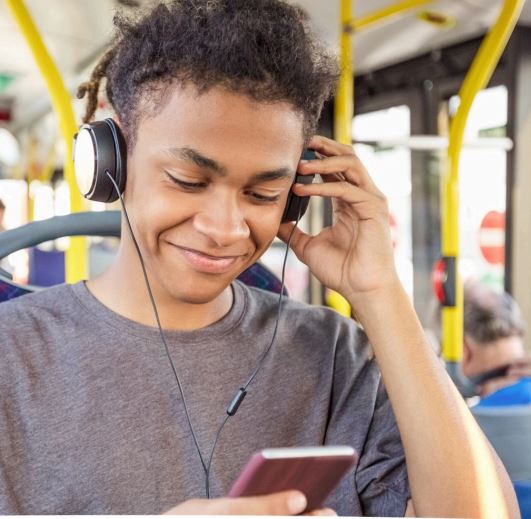 Smiling teen looking at phone while on bus