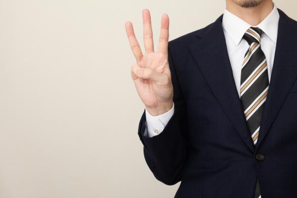 Man in suite holding 3 fingers up