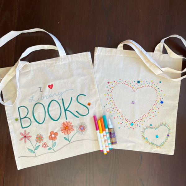 Two tote bags. The first says "books" and has flowers, the second has hearts on it.