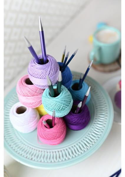 Pastel colored yarn arranged like a cake on a pale blue cake stand.