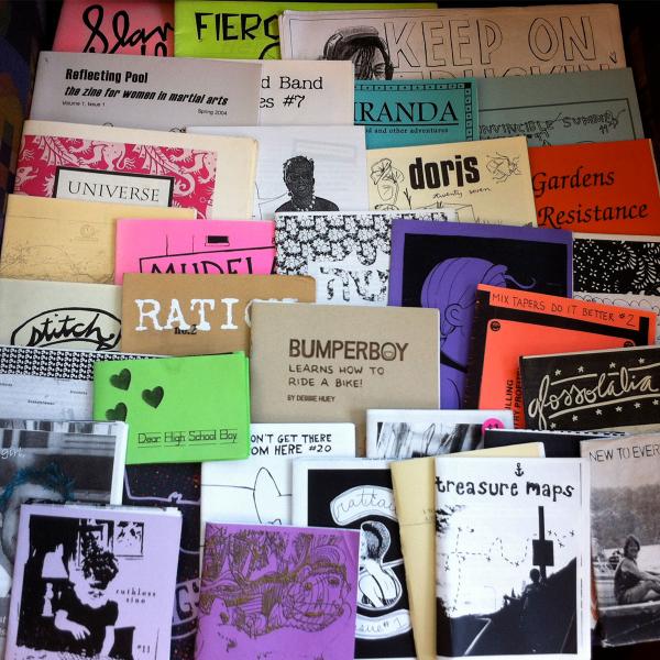 Several dozen zines spread out on a surface