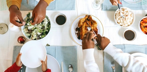 Picture taken from above a kitchen table with hands holding plates and cutting food 