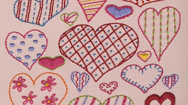 Hearts with various patterns embroidered on a pink background.