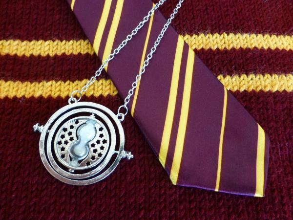 A time-turner pendant sits atop a necktie and sweater in Griffindor stripes of yellow and burgandy.