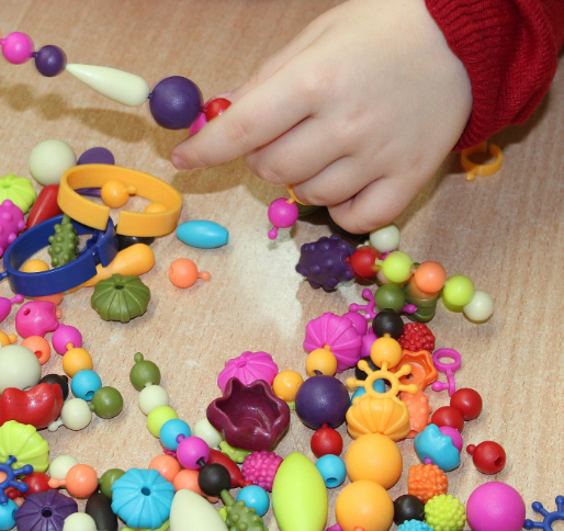 child's hand holding a string of large colorful beads
