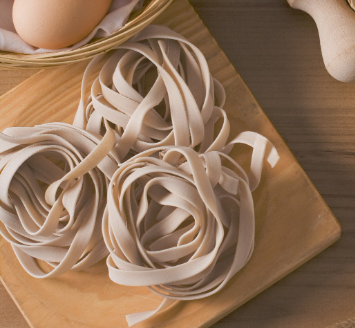 Three nests of pasta on a wood board