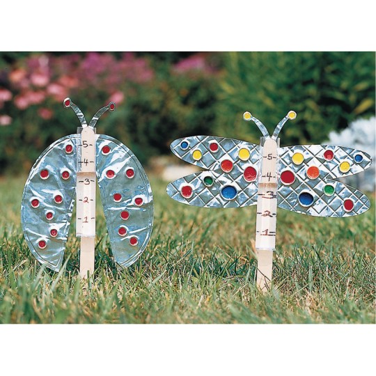 Insect shaped rain gauges with foil wings in grass. 