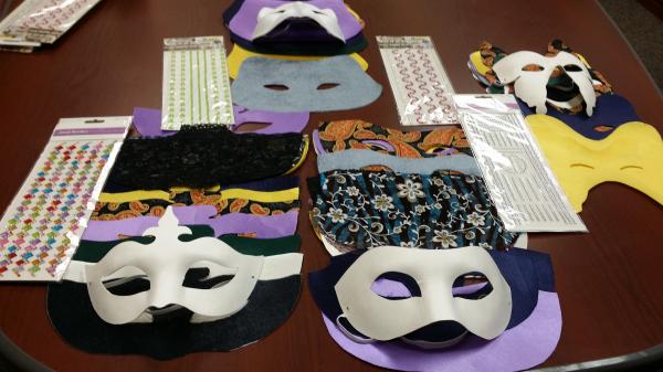 Several masks in various shapes and fabrics laid out on a wooden table.