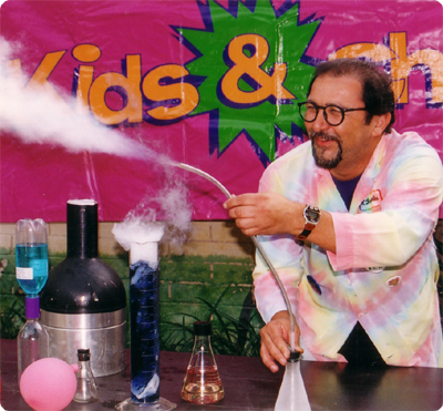 A man in a lab coat holding a tube with steam coming out of it.