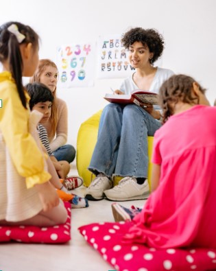 Woman seated in beanbag chair reading to children sitting on mats