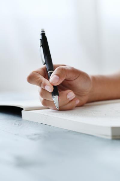 A hand holding a pen writing in a notebook.